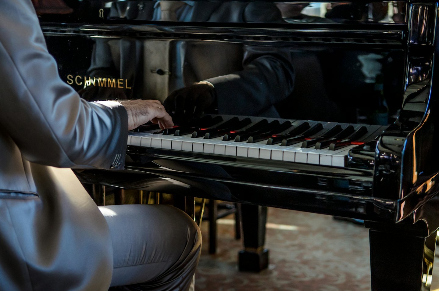 Mani che suonano i tasti di un pianoforte a coda nero.